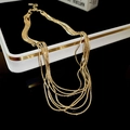 Primer plano de collares bañados en oro en capas sobre una caja de regalo blanca - Dorado