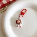 Detailed view of cartoon figure keychain with red hook on a white decorative plate - White Puppy