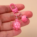 Primo piano di un portachiavi a forma di tartaruga rosa in resina con campanellino - Rosa
