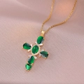 Primer plano del collar de cruz dorado con circonitas verdes y claras sobre tela rosa - Xl2072-5# Cadena De Cruz De Oro Con Diamante Verde