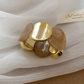 Détail d'un bracelet en acrylique ambré et métal doré sur fond de tulle blanc élégant - Marron