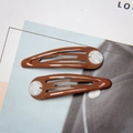 Detail of brown snap hair clips with white shell-like circular resin ornaments - Coffee