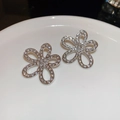 Makroaufnahme silberner hohler Blumenohrringe mit Zirkonia auf weißem Keramikteller - Silbernadel - Silberne Strass Hohlblumen Ohrstecker / Silber