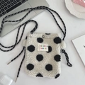 Gros plan sur le sac en peluche à pois noirs et blancs avec bandoulière tissée - Pois sur fond blanc