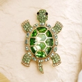 Detailed close-up of a vintage golden turtle brooch with vibrant green crystals and rhinestones - Green