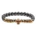 Black hematite beads bracelet with golden skull charm and red eyes on white backdrop - Gold Skull