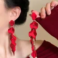 Detail of red rose petal tassel earrings with gold chains on model profile - Chinese Red Petal Tassel Style / Red
