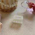 Detail view of a pearlescent white acetate square hair claw clip on soft beige fabric - Small / Jade White