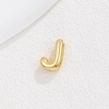 Close-up of a 18K gold plated bubble letter J pendant on a textured white stone surface - Letter J / Gold