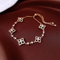 Detail of adjustable gold bracelet featuring green zircon flower links on velvet - Gold-Green