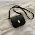 Classic black matte PU saddle crossbody bag with a gold metal lock on a white blazer - Black