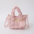 Detalle del bolso de nylon rosa acolchado con lazo dorado y un suave colgante de pompón - Rosa