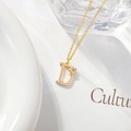 Detail van gouden ketting met letter D hanger met klein bloemaccent en zirkoonsteen - Letter D