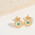 Close-up of golden evil eye gear stud earrings with turquoise and white enamel details - White Evil Eye