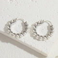 Elegant silver pearl earrings with white beaded detail on natural stone surface - Silver