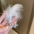 Detalle del pendiente de lazo plateado con diamantes sobre suaves plumas blancas - Gancho de oreja-Lazo Oreja Derecha