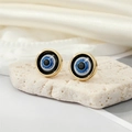 Macro shot of evil eye stud earring with gold rim on natural stone background - Gold Black Glitter Eye