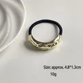 Elastic hair tie with gold textured geometric metal piece and high-stretch black rope - Single Wave Bar Gold