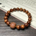 Handcrafted rosewood bracelet featuring carved lucky charm bead and gold spacers - 10mm Bead With Wealth Symbol