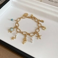 Macro shot of gold ocean-themed bracelet with turtle and pearl charms on jewelry tray - No.8 Light Blue Pendant