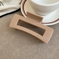 Detail view of the large square hollow hair claw clip in a matte nude finish on felt cloth - Khaki