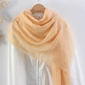 Solid light orange crinkle cotton linen scarf with fringe edges hanging on a white shirt - Apricot