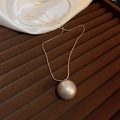 Macro detail of gold-plated snake chain and large pearl pendant on velvet display - Gold Plated Pearl Necklace