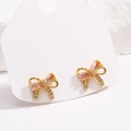 Elegant 18K gold-plated bow earrings with pink zircon and dangling crystals on display - Gold