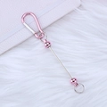 Pink D-ring carabiner with matching beads and metal rod on white plush background - Pink