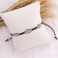 Bohemian woven seed bead bracelet in turquoise and gold on a white display cushion - Black