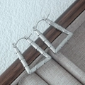 Macro view of silver bamboo texture hoop earrings on a vintage wooden box edge - Silver