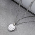 Collier avec pendentif coeur en marbre blanc posé sur un fond texturé gris élégant - Cœur en marbre blanc