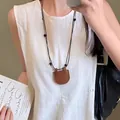 Close-up of a vintage brown leather star pouch pendant necklace on a lifestyle model - 12# Necklace - Coffee - Leather Pocket Shape
