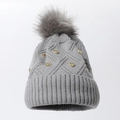 Graue Strickmütze mit großem flauschigem Bommel und goldenen Herznieten auf Weiß - Grau