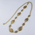 Close-up of bohemian gold metal chain belt with vintage embossed oval plates and hook - Gold