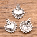Three silver metal Sacred Heart pendants with cross on a rustic wooden background - 28C3-5 Cross Sacred Heart