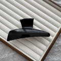 Minimalist glossy black hair claw clip in a large shark fin style on beige display tray - 11.5cm Horn Style / Bright Black