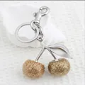 Cherry keychain bag charm with gold sequins and metal hook on a white shell prop - Rich Gold Matte Cherry with Matte Silver