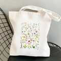 White canvas tote bag featuring colorful yellow cosmos flowers print on a black chair - Colorful Wildflowers