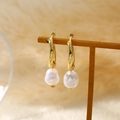 Elegante gouden oorringen met hangende witte barokparels op een sieradenstandaard - Barok Parel Drop Gouden Hoepels