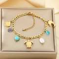 Dettaglio del bracciale dorato con ciondoli a tema marino come tartaruga e conchiglia - Stile Catena Figaro Creature Marine Gemme Viola (KB203138-SXSJ)