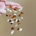 Macro shot of Bohemian style layered fringe earrings with amber beads and white stones - Multi-Layer Amber Tassel Style