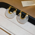 Détail macro de boucles d'oreilles rétro françaises en résine dorée sur un plateau - Blanc