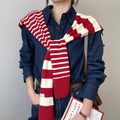 Dettaglio di uno scialle in maglia a righe rosse e bianche sulle spalle con piccola etichetta - Borgogna