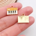 Golden keyboard charm pendant with orange keys showing front and textured back - Piano