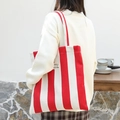 Red and white striped canvas tote bag with thick texture and lettered brand tag - Red