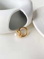 Macro shot of gold-plated layered ring featuring a central white pearl on ceramic - US 6 / Gold