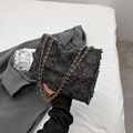 Schwarze Tweed-Umhängetasche mit goldener Kette und Fransenrand in der Hand - Schwarz