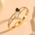 Vue détaillée d'un bracelet doré en acier inoxydable avec charmes de cœur et zircons - Style Double Cœur Incrusté de Coquillage Doré (H817)