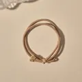 Close-up of khaki braided elastic hair tie with knotted detail and golden metal tips - Dual-strand Simple Style / Milk Coffee
